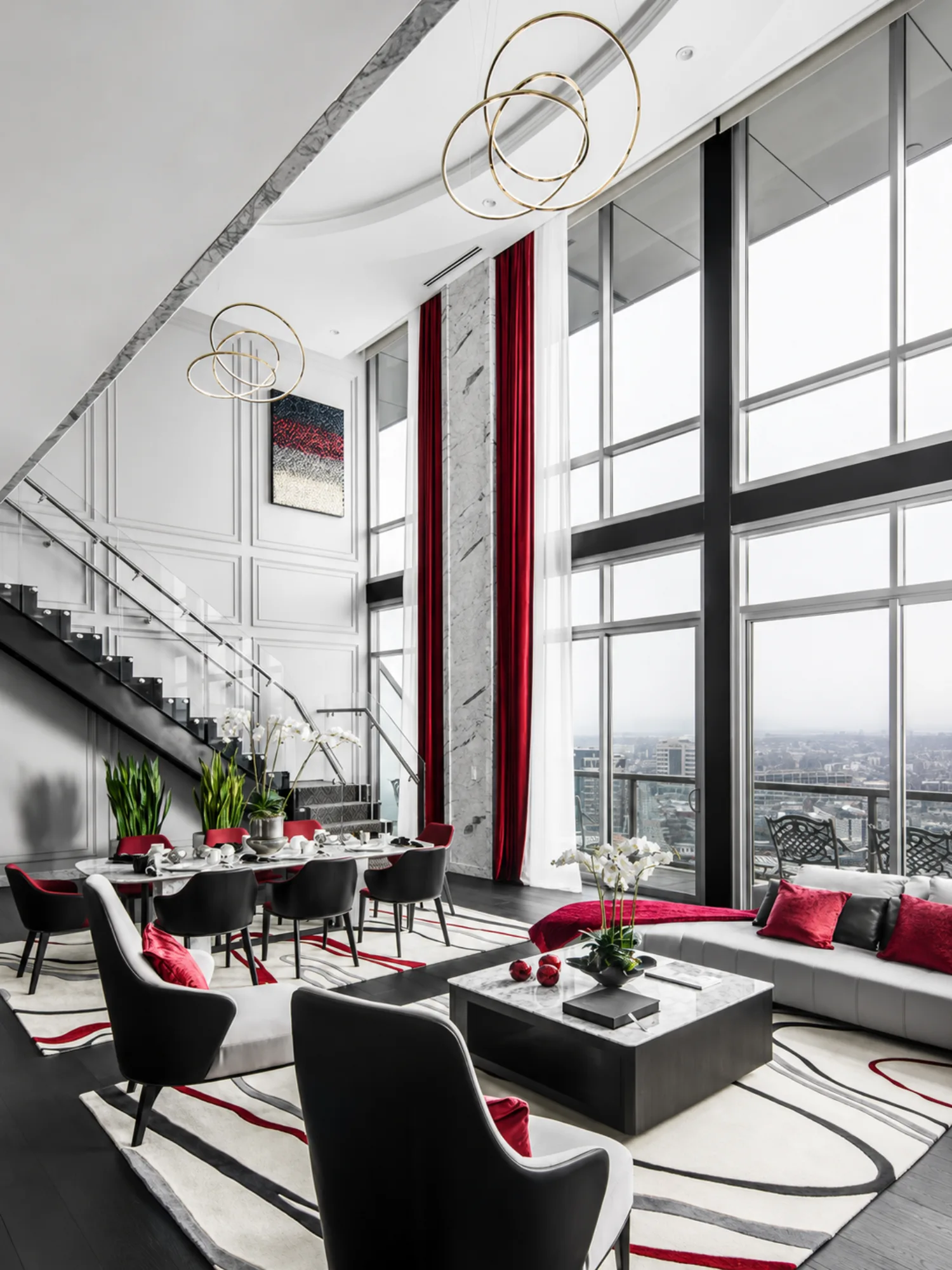 Double-height great room with floor-to-ceiling city windows and red accents