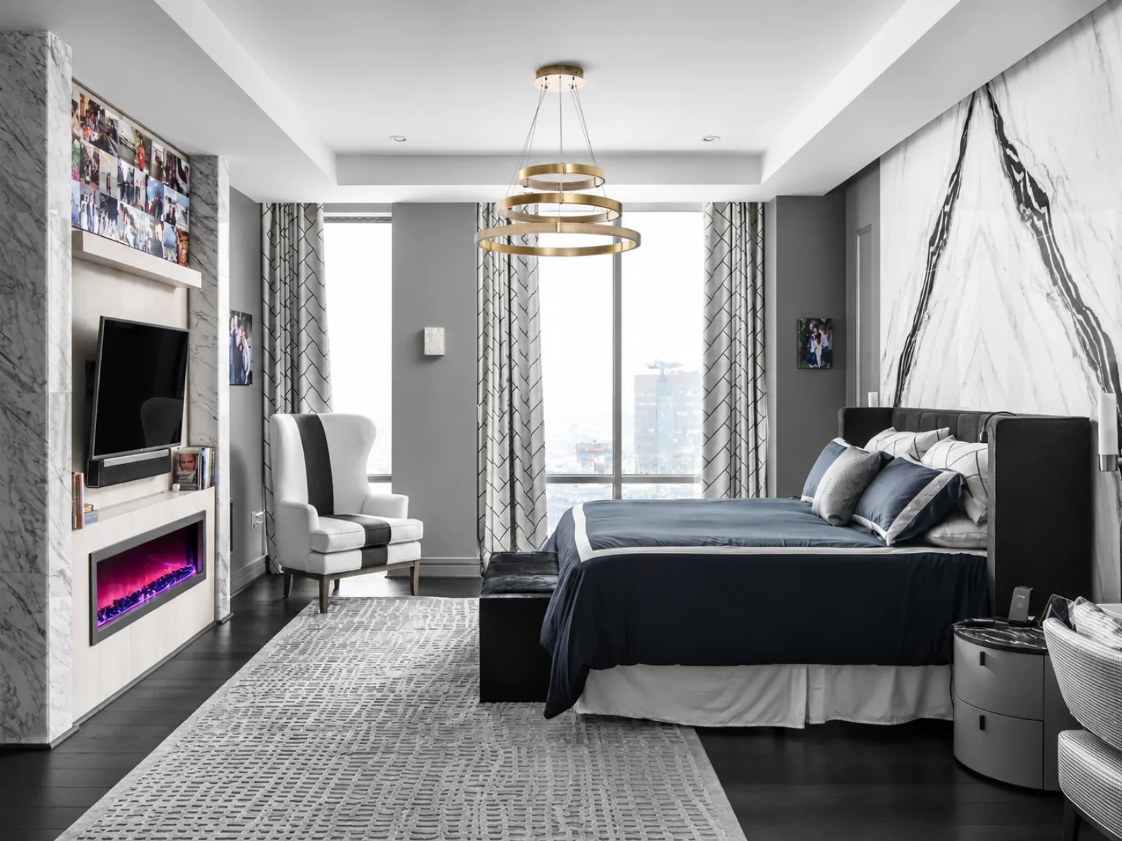 Primary bedroom with blue bedding, a gold ring chandelier, and a marble accent wall